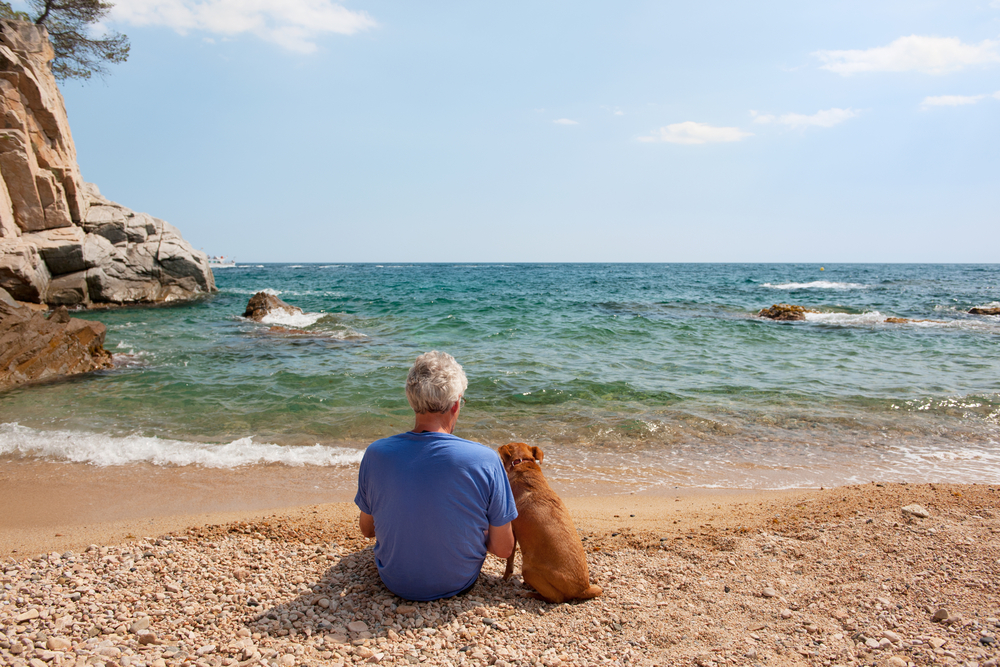 Man met hond op het strand in Spanje